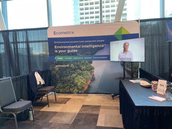 The Ecometrix booth at ICARD 2024 with an Ecometrix branded banner, video, and table.