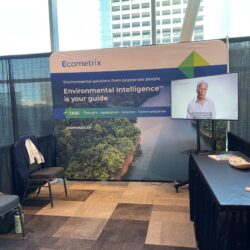The Ecometrix booth at ICARD 2024 with an Ecometrix branded banner, video, and table.
