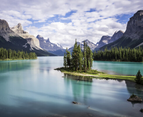 An island in the middle of a lake with mountains in the background.