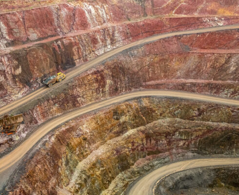 An open mine with haul truck driving up road.