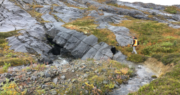 Jonathan Keizer in the field, surrounded by rocks and grass.